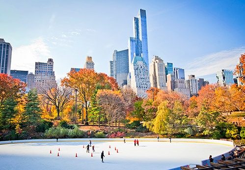 people ice skating in central park with skyscrapers in the background
