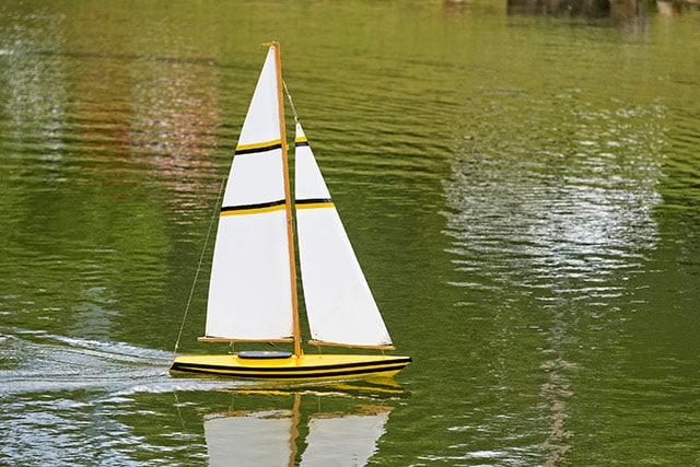 yellow model sail boat on water
