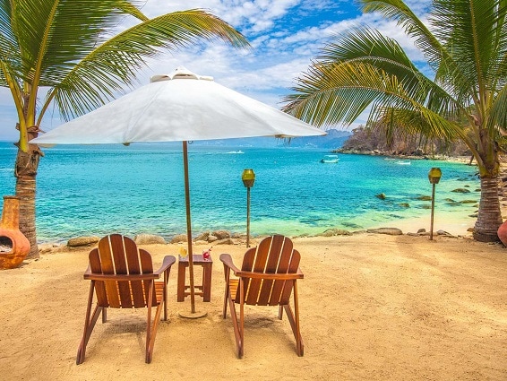 wooden beach chairs and white umbrella on las caletas beach