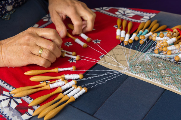 woman making a blue and white mundillo by hand in san juan