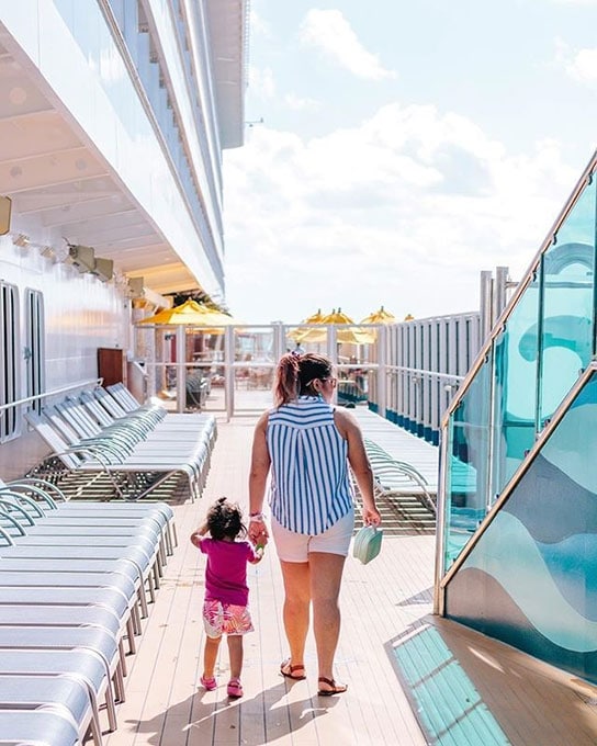 mother and daughter holding hands as they walk along the cruise deck