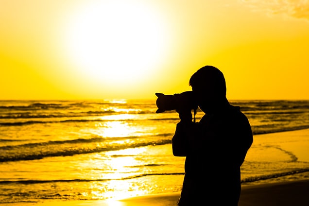 man taking scenic photographs of sunset in a beach of bonaire