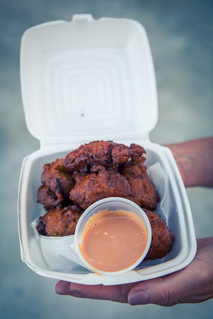 conch fritters with pink sauce in a to-go box from st. kitts