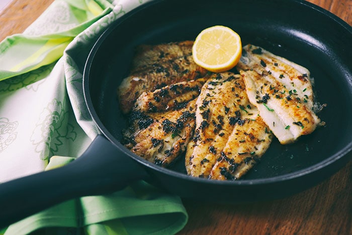 4 fishes cooked on a pan with lemon