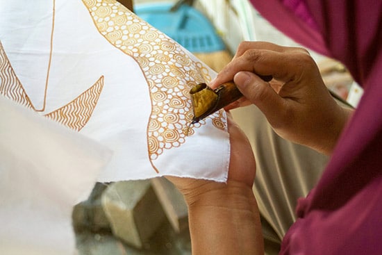 woman adding batik designs on a white cloth in princess cays