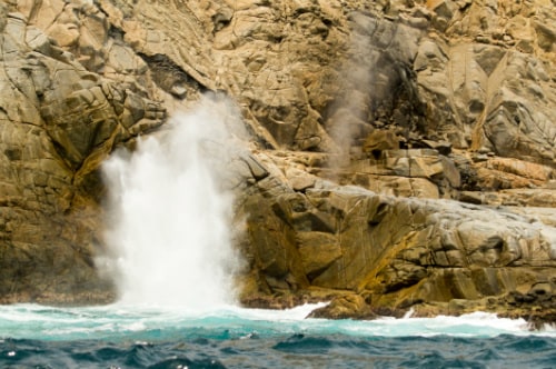 one of the biggest marine geysers in the world, la bufadora, ejecting column of hot water and steam