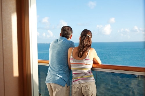 couple enjoying the view of the caribbean sea from their balcony onboard a carnival ship