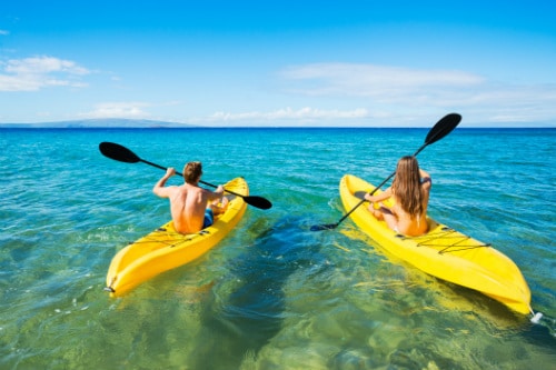 man and woman on yellow kayaks, kayaking off the shore of hilo hawaii