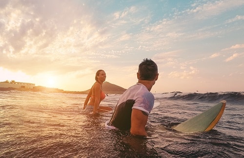 fit couple surfing off the coast of honolulu hawaii 