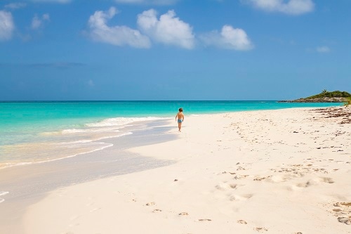 little boy running along the shore in smith’s point beach, freeport bahamas