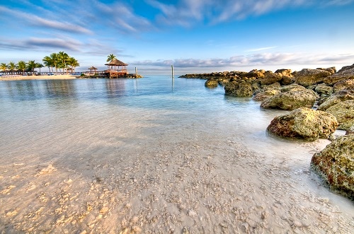 rocks and pier on the crystal clear waters of a beach in nassau bahamas