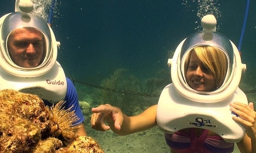 couple looking at coral reef as they helmet diving in the caribbean 