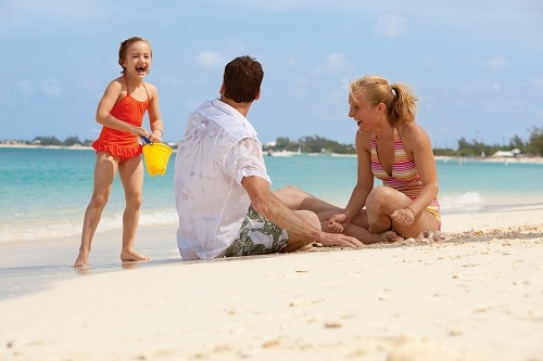 parents playing on a beach in the southern caribbean with their daughter
