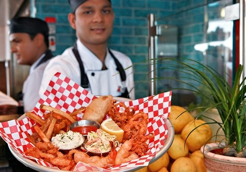 server holding a plate of fried sea food from seafood shack 
