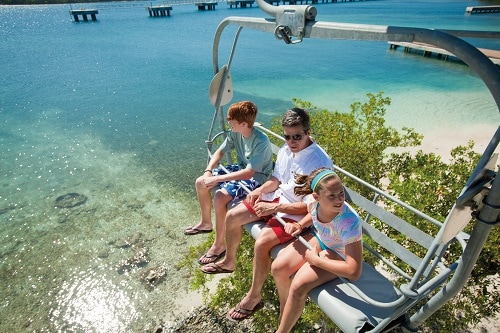 father and 2 children going up a chair lift in the caribbean