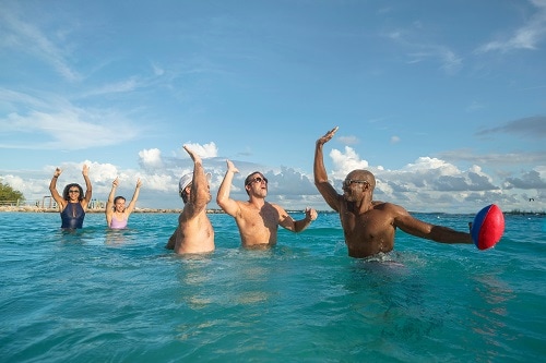 friends giving each other a high five as they throw a football around in the ocean