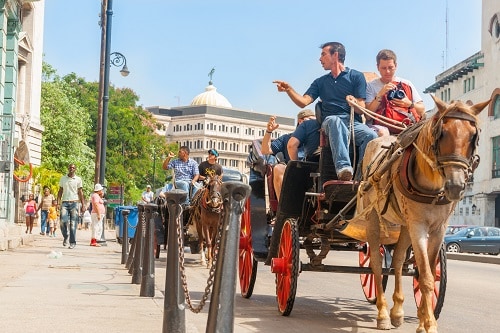 guests touring a caribbean city on horse and buggy with the help of a tourist guide