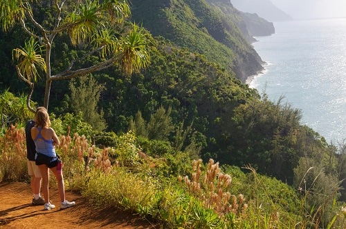 couple wearing athletic clothing looking over the hawaiian coast line during a hike
