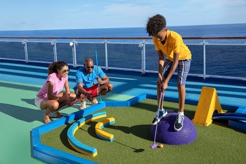 parents watching their son play mini golf on board carnival dream