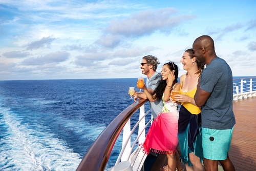 friends enjoying the ocean view by the railing of a carnival ship