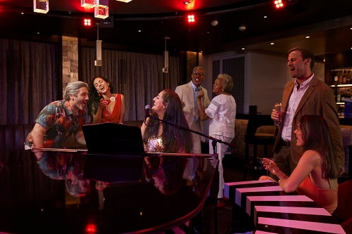 people dancing and singing along to songs at the piano bar