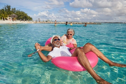 senior couple floating along the beach on a pink tube