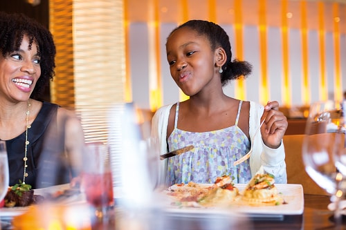 a girl enjoying her food onboard carnival’s steakhouse