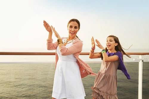 mother and daughter dancing by the rail of a carnival ship
