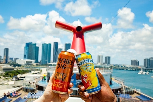two people cheering their beers onboard a carnival ship