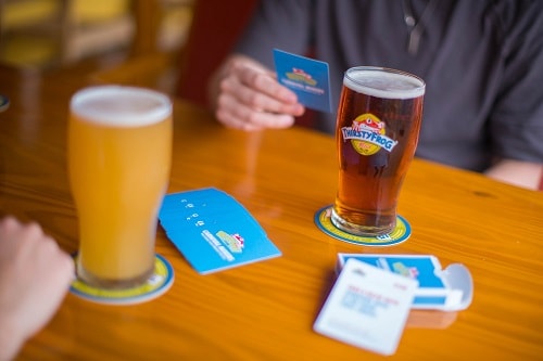 two people playing a card game and having exclusive brews