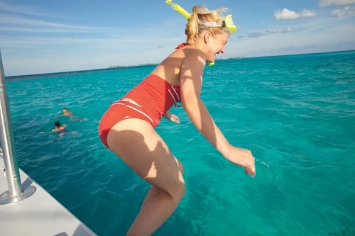 woman about to jump into the water with her snorkel mask on
