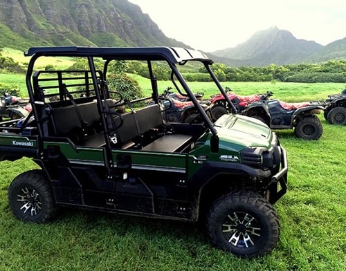 a hawaiian valley with a golf cart and ATVs in the background