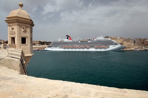 a carnival ship pulling into the port of valletta, malta