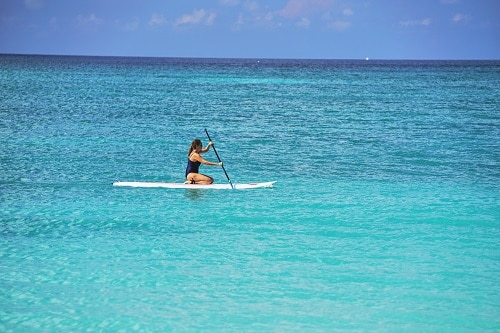woman paddle boarding across the oceans of grand cayman