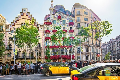 a full view of the casa batllo with roses hanging off the balconies in barcelona