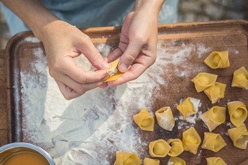 a person rolling up tortellini pasta by hand