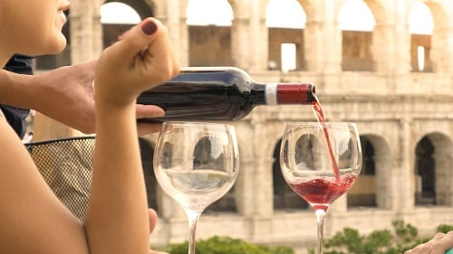 a young lady enjoying a glass of wine in front of the coliseum 