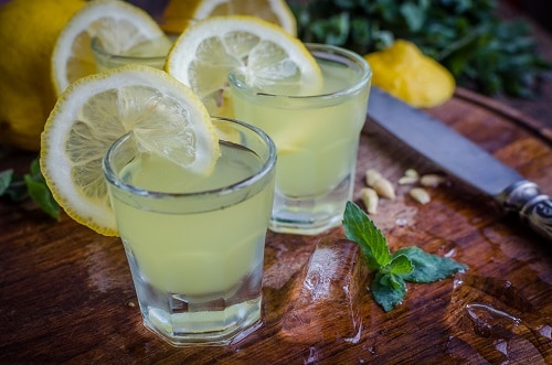 two glasses of limoncello with a lemon attached to them