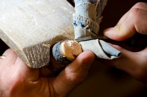 a craftsman hand carving a cameo figure out of seashell