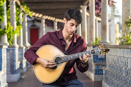 a fado musician playing a portuguese guitar