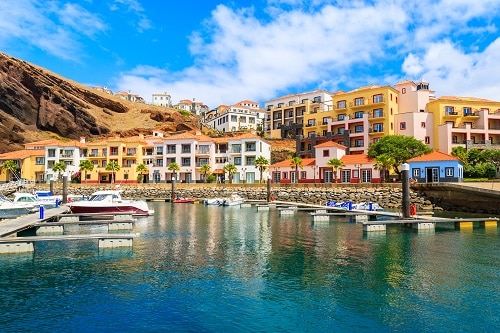 boats in a marina with colorful houses on the madeira coast in portugal