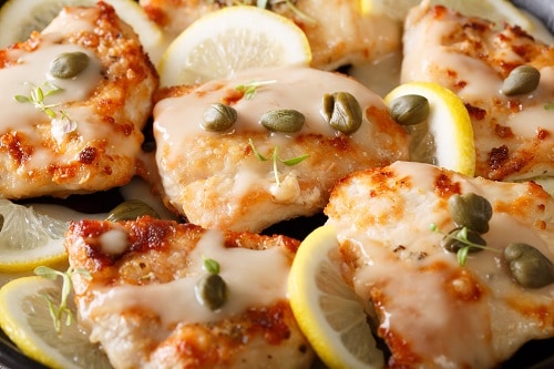 a lemon chicken dish with small, green, capers on top