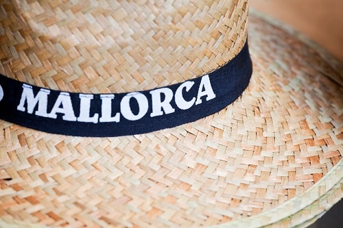 a straw hat with a black band that says mallorca on it
