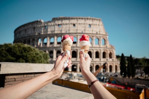 couple holding their gelatos in front of the colosseum
