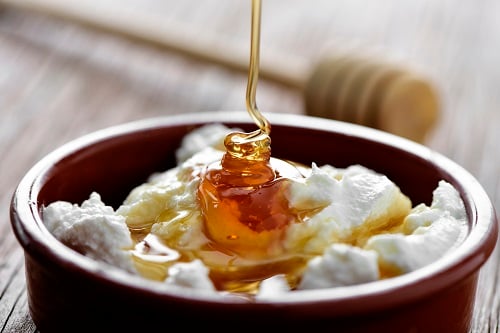honey being drizzled on top of a mel i mato, a catalonian dessert