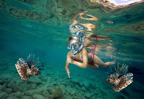 young girl snorkeling with lionfish