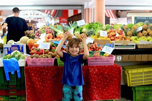 child playing with pineapples at a marketplace in noumea