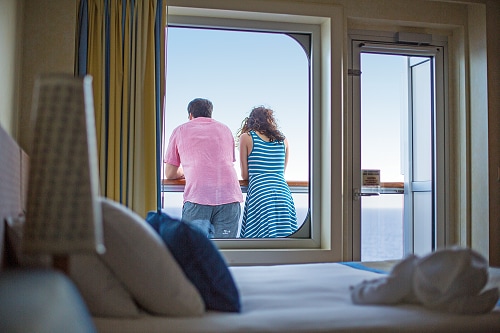 couple looking at the ocean from their balcony stateroom