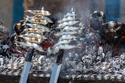 espetos, or sardines, roasting on a barbeque in malaga, spain