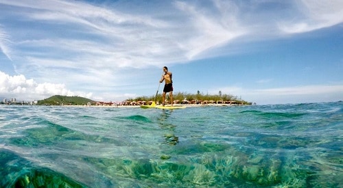 a man paddle boarding in anse vata beach